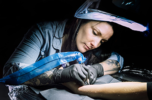 Une tatoueuse en train de tatouer